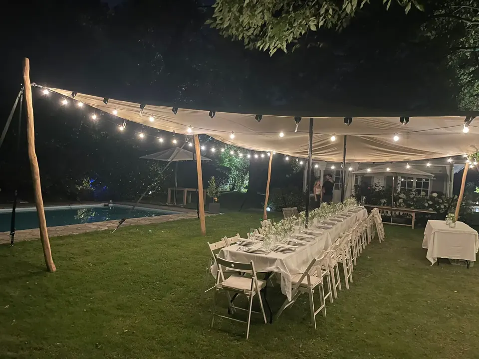 Stretchzelt am Abend mit Lichterketten über einer langen Tafel