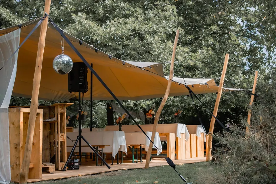 Stretchzelt mit Lichterketten und gedeckter Tafel bei einer Gartenhochzeit – Piumer Eventverleih